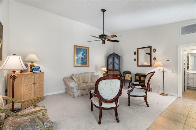 living area featuring visible vents, baseboards, light colored carpet, light tile patterned floors, and a ceiling fan