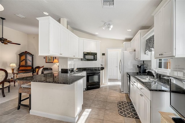 kitchen featuring visible vents, black appliances, a peninsula, white cabinetry, and a sink