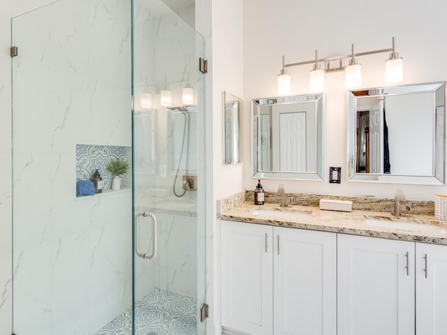 bathroom with a marble finish shower, double vanity, and a sink