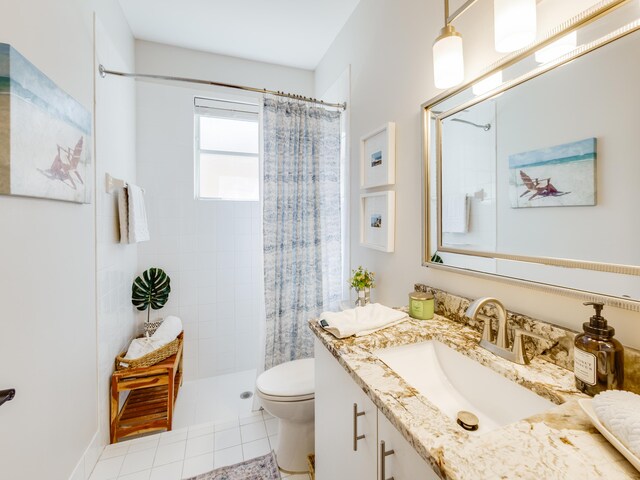 bathroom with tile patterned floors, toilet, vanity, and a tile shower