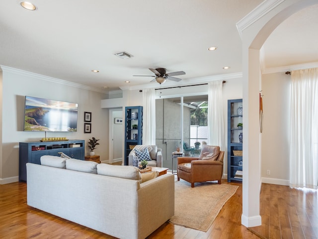 living room with visible vents, arched walkways, ornamental molding, ceiling fan, and light wood-style floors