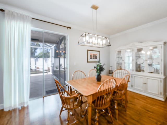 dining area featuring crown molding, an inviting chandelier, and wood finished floors