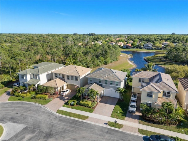 birds eye view of property with a wooded view, a water view, and a residential view