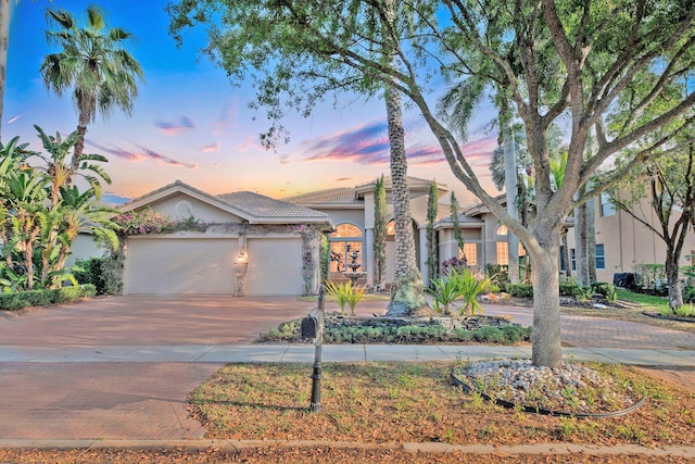 view of front of home with a tiled roof, stucco siding, driveway, and an attached garage