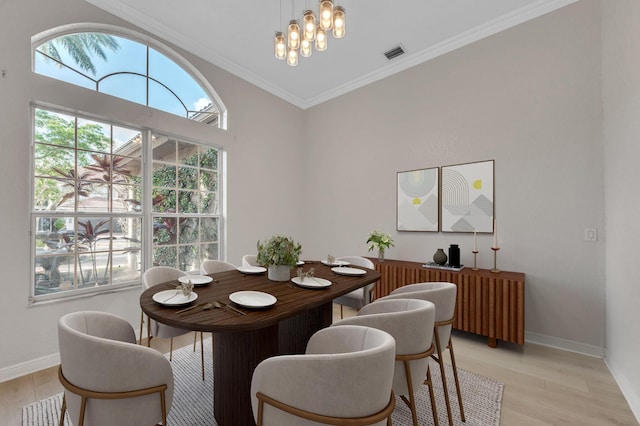 dining room with light wood-style flooring, baseboards, visible vents, and ornamental molding