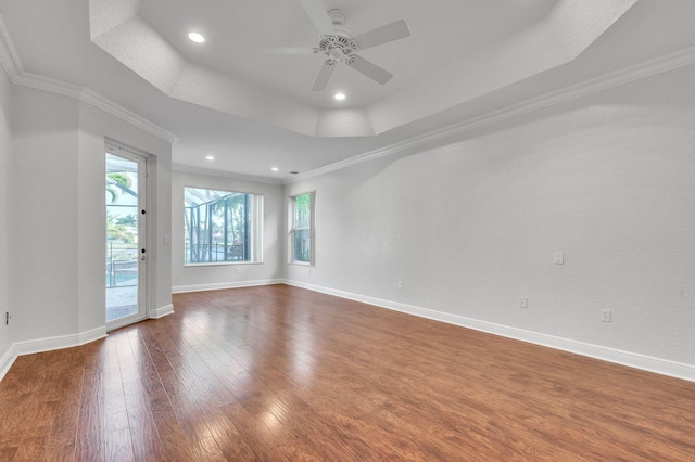 spare room featuring ceiling fan, baseboards, ornamental molding, a raised ceiling, and wood-type flooring