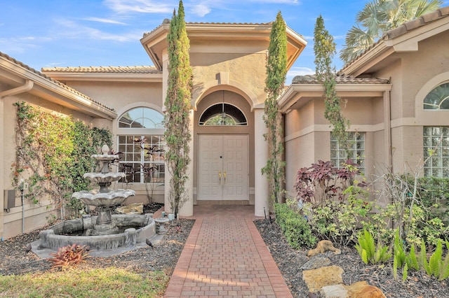 property entrance with stucco siding and a tiled roof