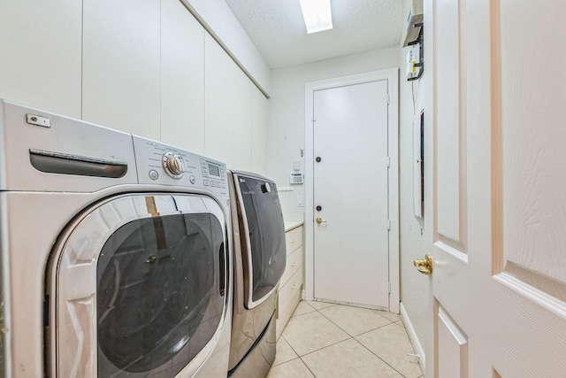 washroom with light tile patterned floors, laundry area, washing machine and dryer, and a textured ceiling