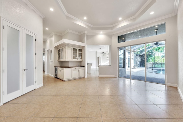 interior space featuring dark countertops, glass insert cabinets, a tray ceiling, and ornamental molding