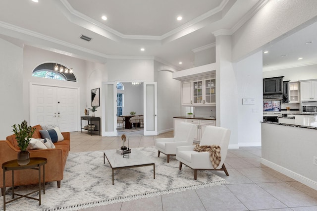 living room with light tile patterned floors, visible vents, a tray ceiling, and ornamental molding