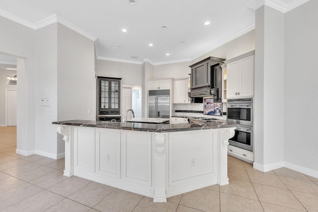 kitchen with stainless steel appliances, dark stone counters, crown molding, light tile patterned floors, and decorative backsplash