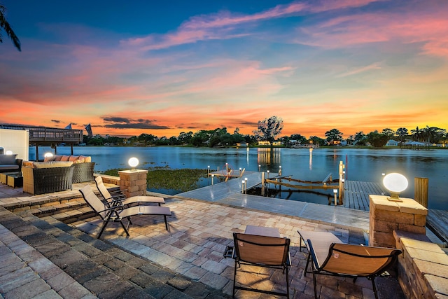 dock area with a water view, boat lift, and a patio area