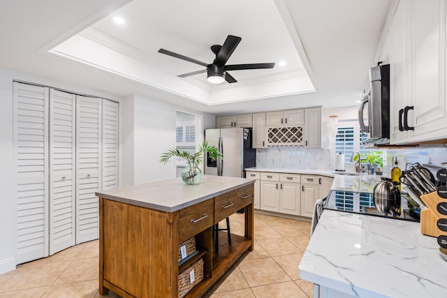 kitchen featuring light tile patterned floors, a ceiling fan, open shelves, appliances with stainless steel finishes, and a raised ceiling