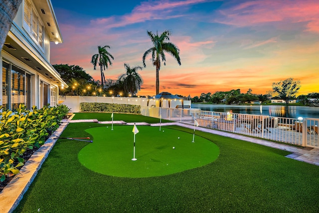 view of property's community with a lawn, a fenced backyard, and a water view