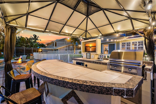 view of patio featuring a sink, exterior kitchen, fence, and grilling area