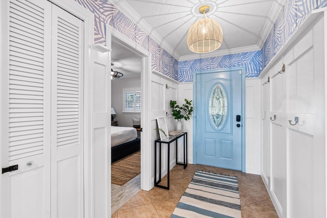 foyer entrance with light tile patterned floors, ornamental molding, and wallpapered walls