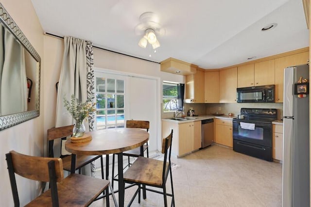 kitchen featuring light brown cabinetry, black appliances, light countertops, and a sink