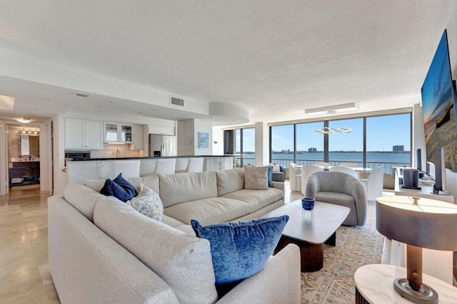 living area with light tile patterned flooring, visible vents, a textured ceiling, and expansive windows