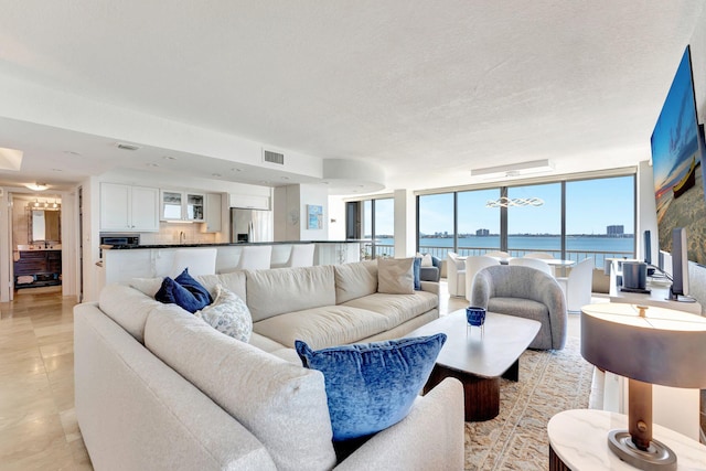 living area with a wall of windows, light tile patterned floors, visible vents, and a textured ceiling