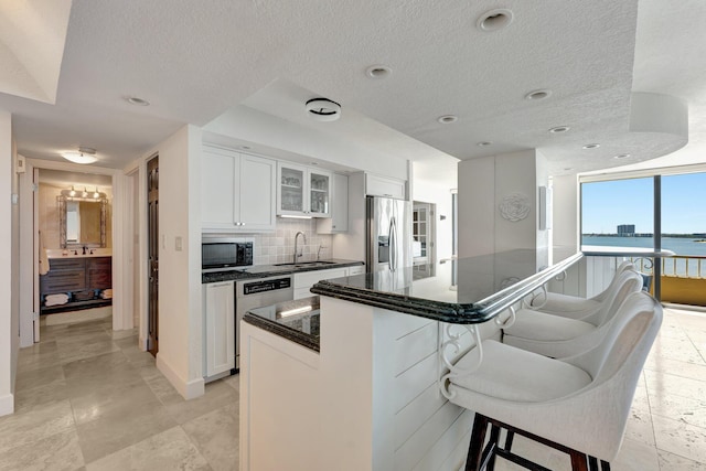 kitchen with decorative backsplash, a sink, a kitchen breakfast bar, stainless steel appliances, and glass insert cabinets