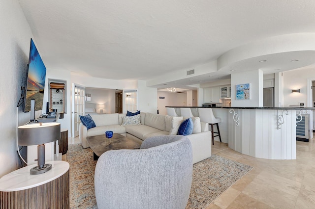 living area with wine cooler and a textured ceiling