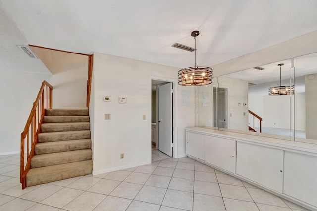 unfurnished dining area with light tile patterned floors, baseboards, visible vents, stairs, and a notable chandelier