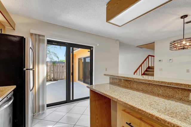 kitchen with pendant lighting, a textured ceiling, appliances with stainless steel finishes, an inviting chandelier, and light tile patterned floors