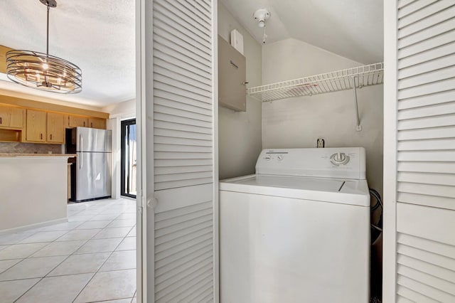 laundry room with a textured ceiling, washer / dryer, light tile patterned floors, and laundry area