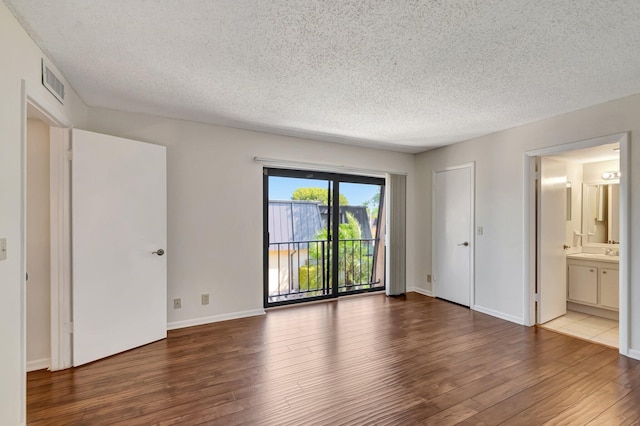 unfurnished bedroom with access to outside, wood finished floors, visible vents, and a textured ceiling