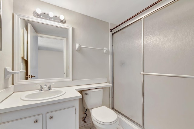 full bathroom featuring vanity, a shower stall, and toilet