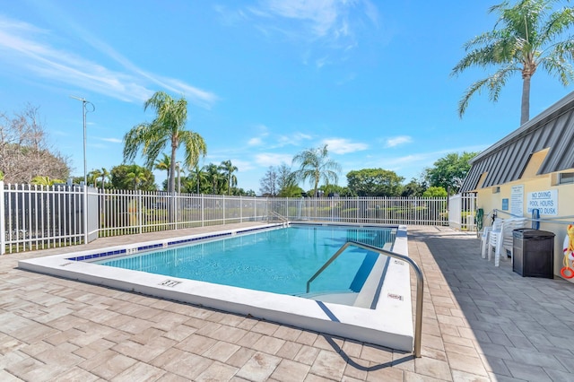 community pool with a patio area and fence