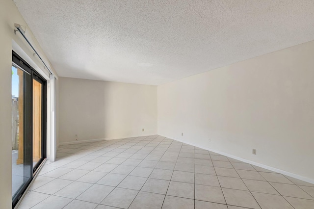 unfurnished room featuring baseboards, a textured ceiling, and light tile patterned flooring