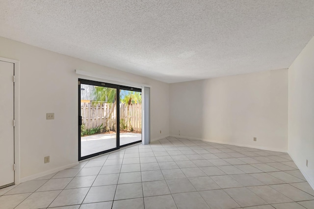 spare room with light tile patterned floors, baseboards, and a textured ceiling