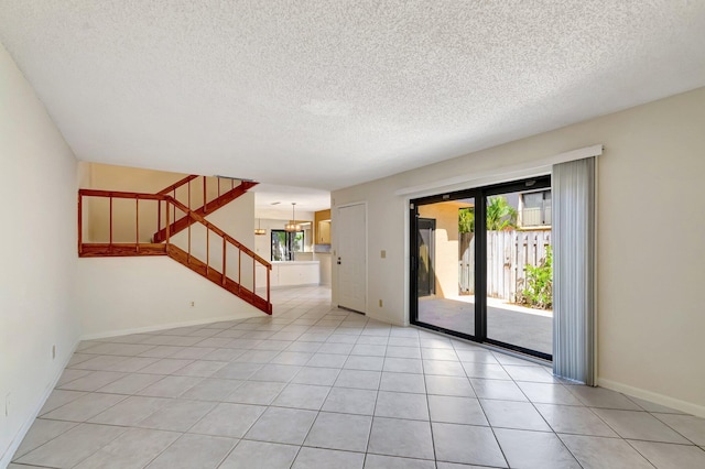 unfurnished room featuring stairs, light tile patterned floors, and a textured ceiling