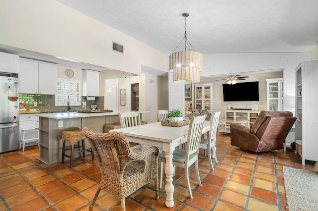 dining area with visible vents, ceiling fan with notable chandelier, a textured ceiling, and lofted ceiling