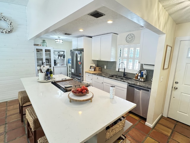 kitchen featuring visible vents, a breakfast bar, stainless steel appliances, a textured ceiling, and a sink