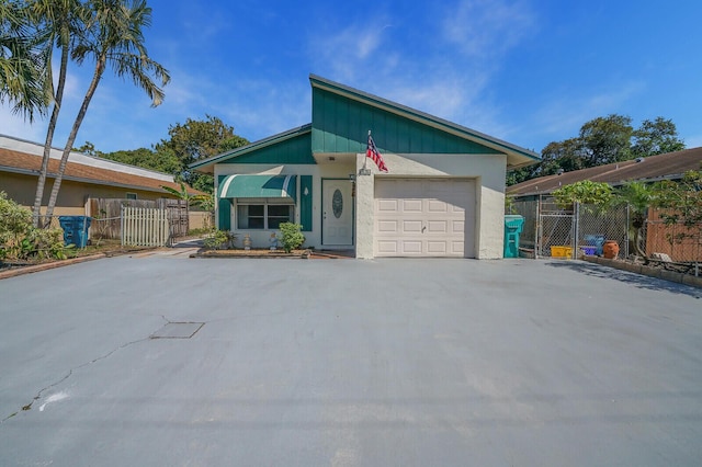 view of front facade featuring an attached garage, a gate, fence, and driveway