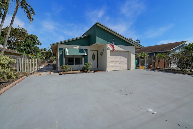 view of front of property with concrete driveway, an attached garage, and fence