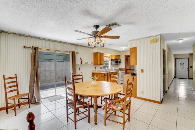 dining space with wallpapered walls, light tile patterned floors, visible vents, and ceiling fan