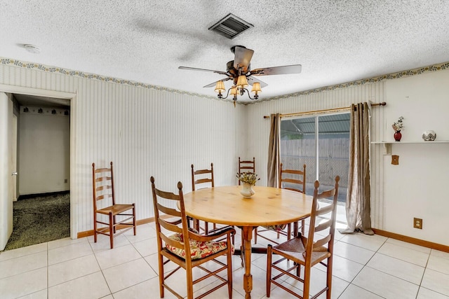 dining space featuring visible vents, baseboards, light tile patterned flooring, a textured ceiling, and a ceiling fan