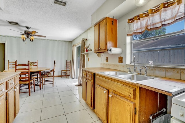 kitchen featuring light tile patterned floors, visible vents, tile countertops, and a sink