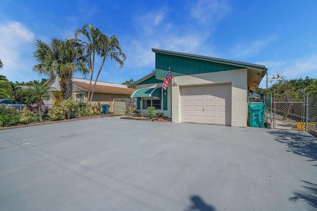 view of front of home with fence, stucco siding, a garage, driveway, and a gate