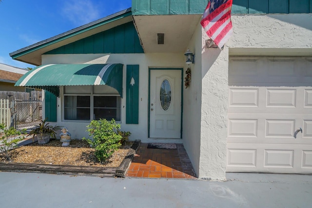 doorway to property featuring stucco siding and fence