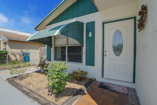 entrance to property with stucco siding and fence