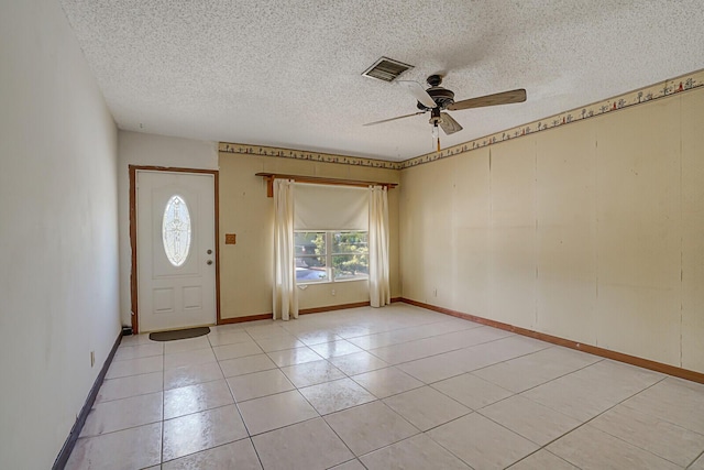 foyer with visible vents, a ceiling fan, a textured ceiling, light tile patterned floors, and baseboards