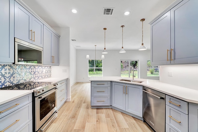 kitchen featuring visible vents, gray cabinetry, decorative backsplash, appliances with stainless steel finishes, and a sink