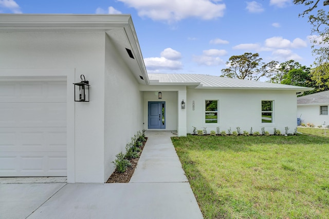 1085 26th St, Vero Beach, FL 32960 - property entrance with a yard, metal roof, stucco siding, and an attached garage