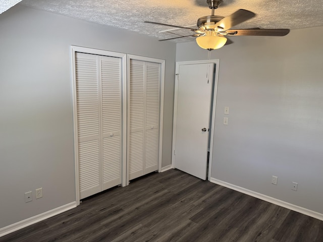 unfurnished bedroom with two closets, ceiling fan, baseboards, dark wood finished floors, and a textured ceiling