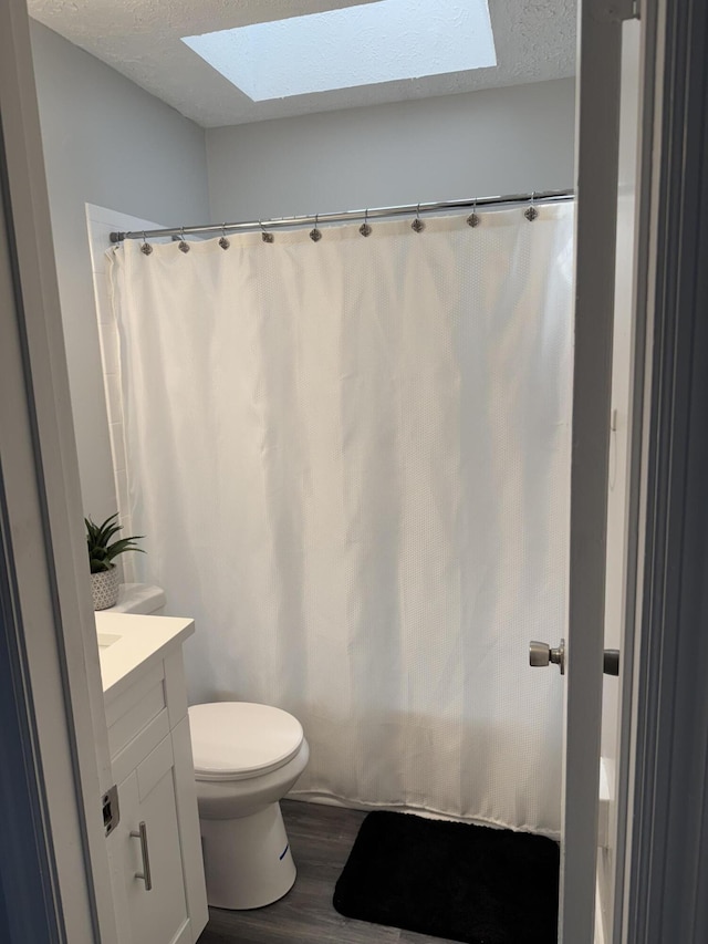 bathroom with vanity, a skylight, wood finished floors, and a textured ceiling