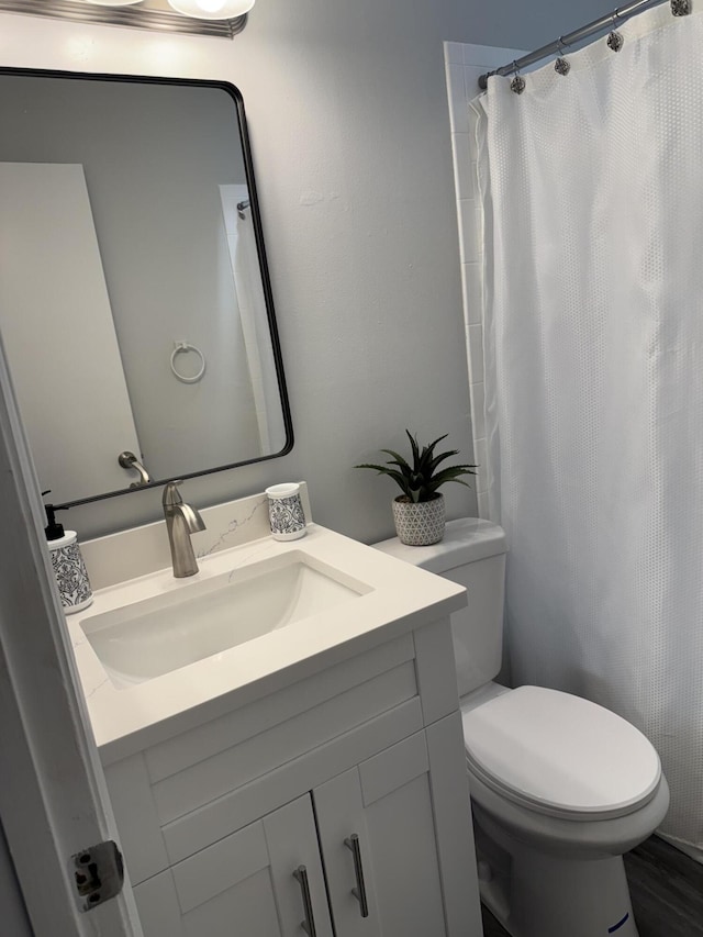 full bath featuring a shower with shower curtain, toilet, and vanity